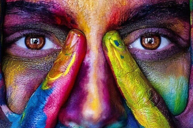 A person with multi-coloured paints on their face