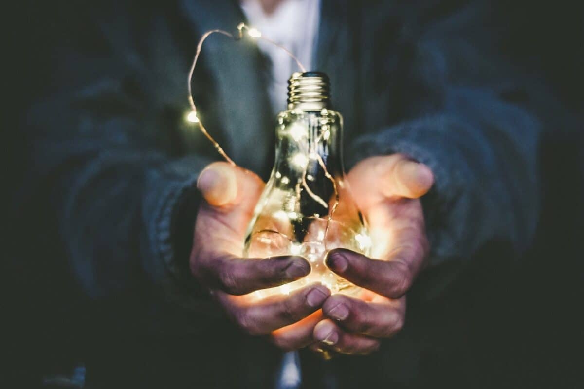Someone holding a lit lightbulb in their hands