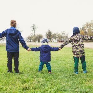 3 young people holding hands in a field