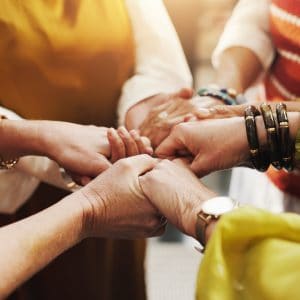 Four women holding hands in prayer